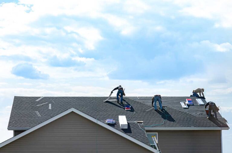 Homeowner reviewing roof warranty papers beside inspection photos and a roofing folder.